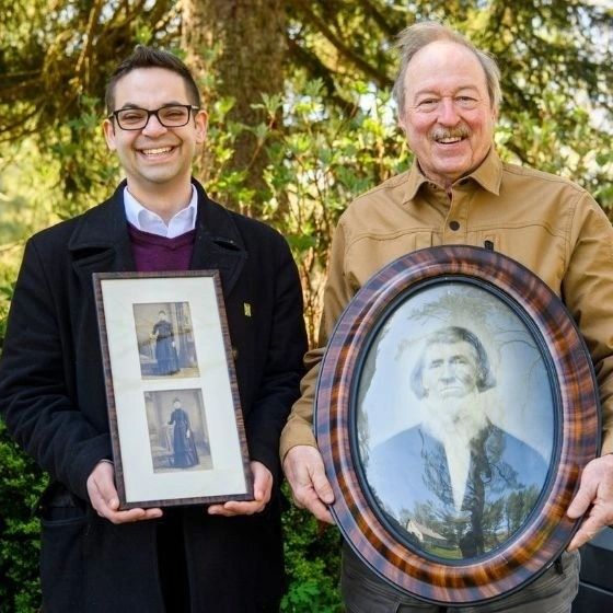 Founders Travis Wade and Mike Baker holding portraits of Clear View Farm’s original homesteaders